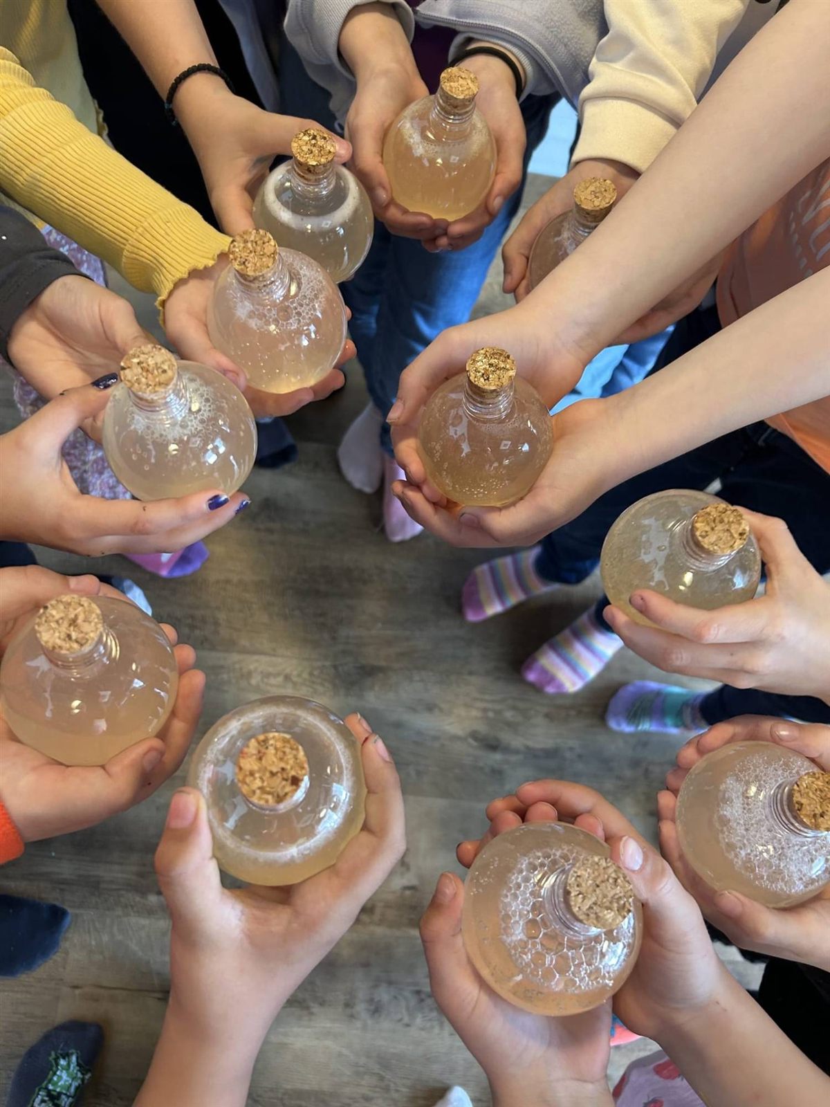 Kinder halten im Kreis selbst gefüllte Flaschen mit Korken